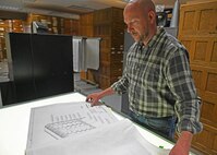 Ryan Laugherym an engineer, examines paper blueprints in a archive.