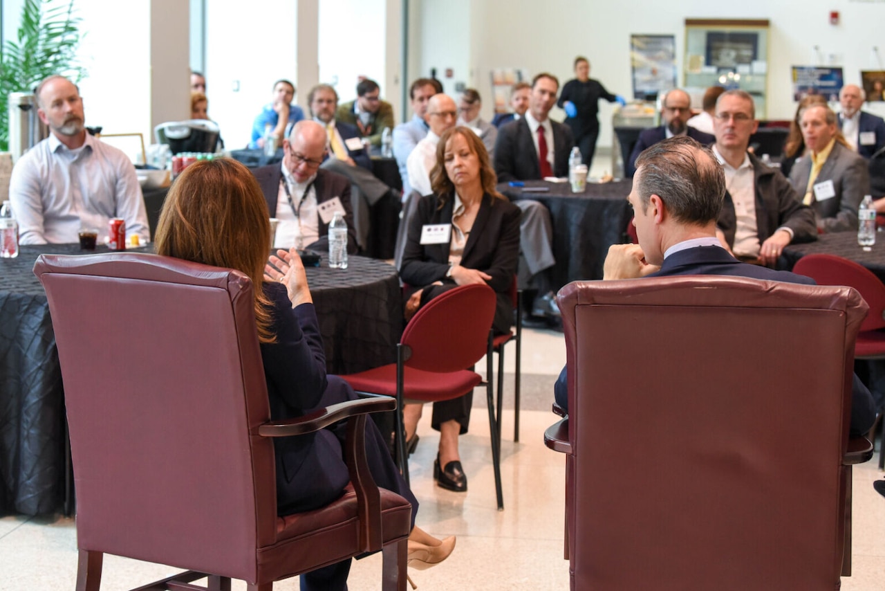 A crowd of people sit in chairs in a large room.