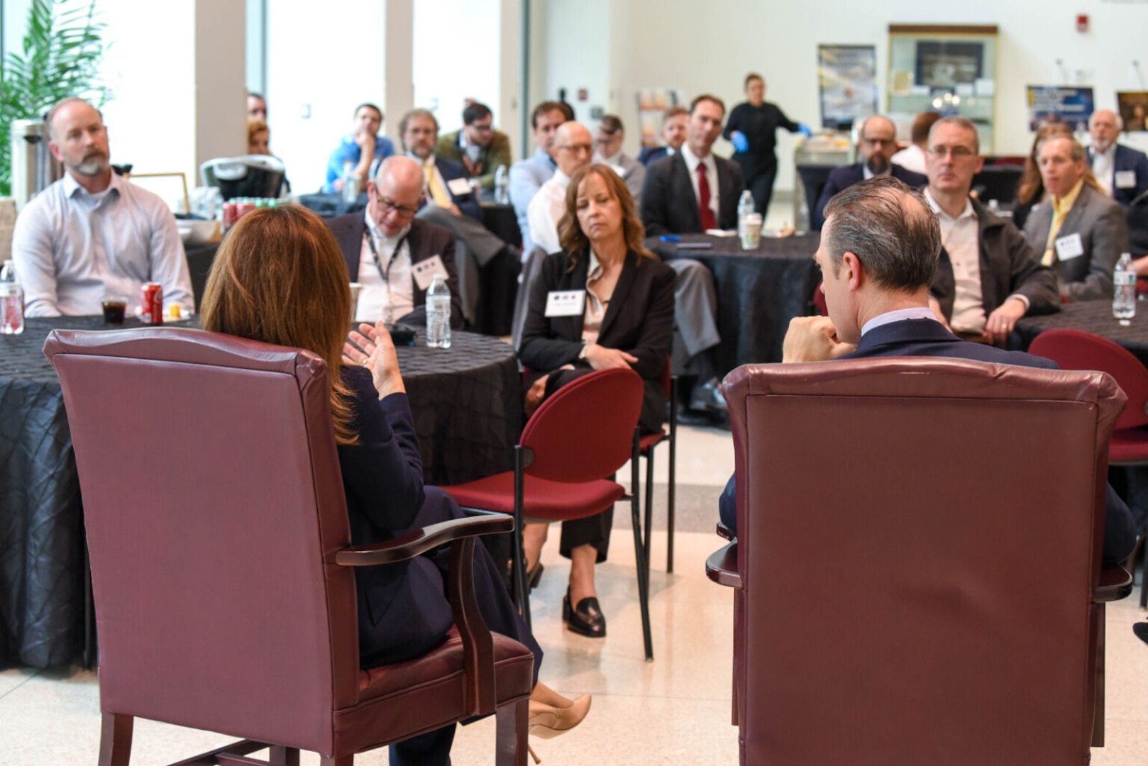 A crowd of people sit in chairs in a large room.