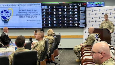 Airmen giving a briefing during AFIMSC IWEPTAC event to leadership in conference room.