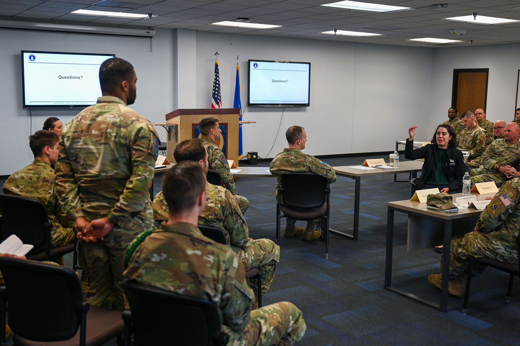 A Guardian stands while Dalton speaks in a conference room.