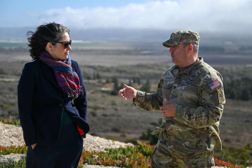 Two military officials speak outside overlooking a valley.