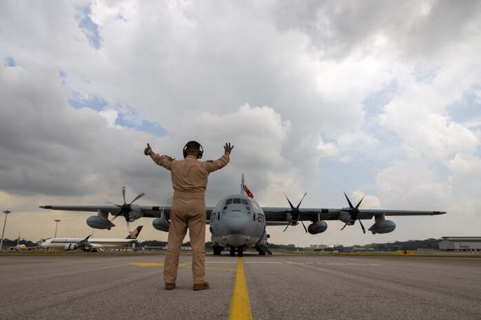 U.S. Marine Corps Master Gunnery Sgt. Christian Villalobos, a KC-130J Super Hercules flight engineer with Marine Aerial Refueler Transport Squadron (VMGR) 352, Marine Aircraft Group 11, 3rd Marine Aircraft Wing, communicates with pilots during engine startup prior to takeoff at Changi Airport, Singapore, Sept. 9, 2024. VMGR-352 stopped in Singapore while flying from Marine Corps Air Station Miramar, California to Camp Lemonnier, Djibouti, to deliver essential personnel, supplies and equipment to 3rd MAW squadrons deployed in support of Combined Joint Task Force-Horn Africa. (U.S. Marine Corps photo by Sgt. Emeline Swyers)