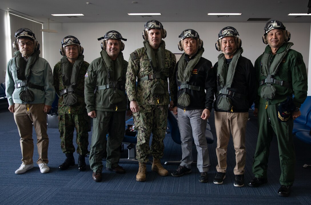 Kazuo Kabatani, director general of the Iwakuni Prefectural Citizens Bureau, left, Japan Ground Self-Defense Force Col. Kenji Murakami, the deputy commanding general of 13th Brigade, U.S. Marine Corps Col. Richard Rusnok, the commanding officer of Marine Corps Air Station Iwakuni, U.S. Navy Rear Adm. Ian Johnson, the commander of U.S. Naval Forces Japan, Yoshihiko Fukuda, the mayor of Iwakuni city, Hiroyuki Tajitsu, director general of the Chugoku-Shikoku Defense Bureau, and Japan Maritime Self-Defense Force Rear Adm. Ichiro Ishikawa, the commander of Fleet Air Wing 31, pose for a photo at Marine Corps Air Station Iwakuni, Japan before embarking on a flight to the USS George Washington, Nov. 10, 2024. Distinguished visitors from the Iwakuni city government, Japan Maritime Self-Defense Force, and Japan Ground Self-Defense Force embarked on a tour of the aircraft carrier USS George Washington (CVN 73) to observe the ship’s capabilities, cultivate bilateral defense relationships, and demonstrate the joint force’
