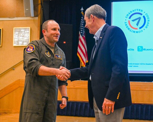 U.S. Air Force Col. Matthew Kenkel, left, 35th Fighter Wing deputy commander, coins retired Col. Lee Ellis, former Vietnam War pilot and prisoner of war, after a presentation at Misawa Air Base, Japan, Nov. 15, 2024.