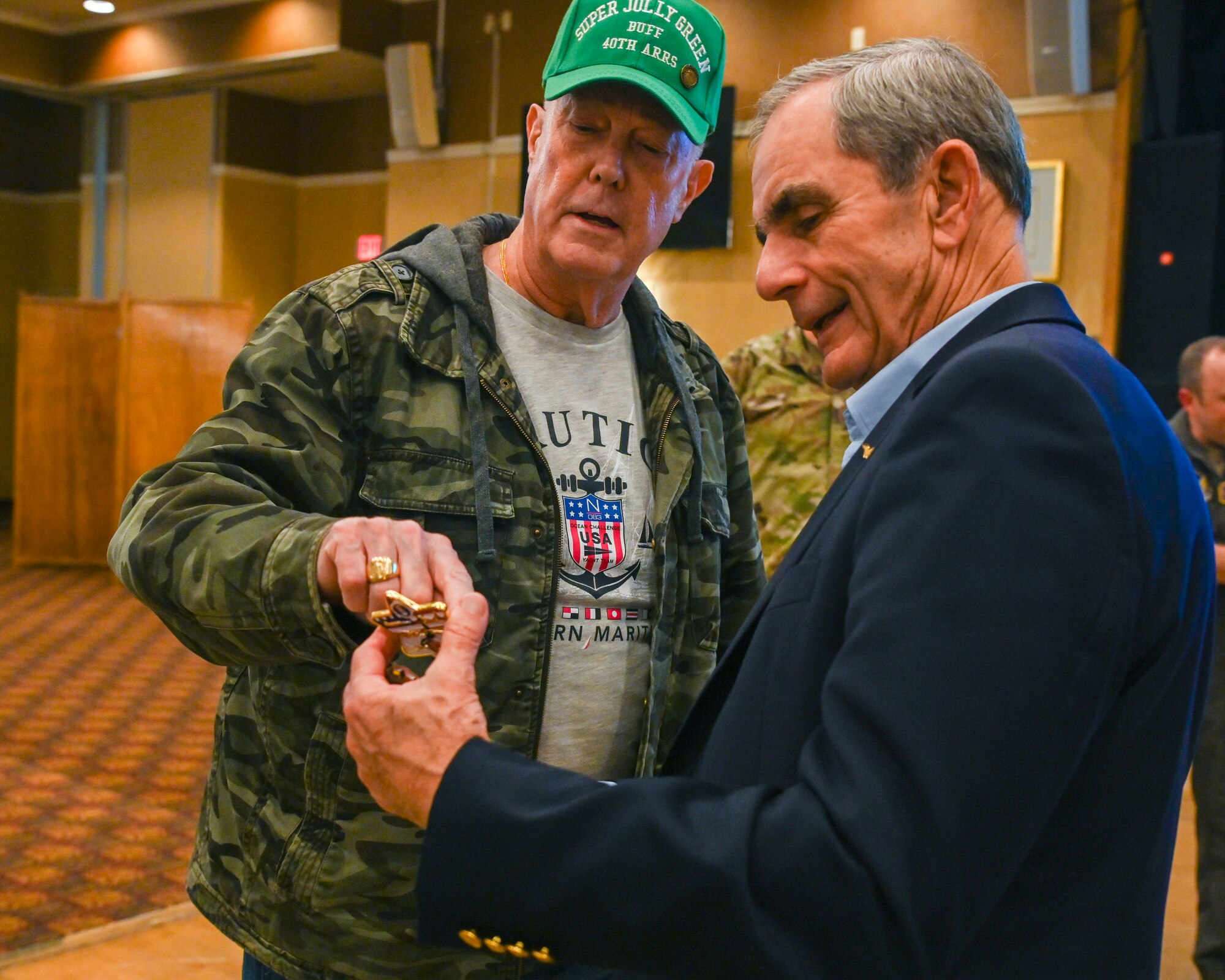 U.S. Air Force retired Chief Master Sgt. David Barton, left, Retirees Activities Office director, gives a coin to retired Col. Lee Ellis, former Vietnam War pilot and prisoner of war, as a gesture of gratitude following his presentation at Misawa Air Base, Japan, Nov. 15, 2024.