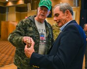 U.S. Air Force retired Chief Master Sgt. David Barton, left, Retirees Activities Office director, gives a coin to retired Col. Lee Ellis, former Vietnam War pilot and prisoner of war, as a gesture of gratitude following his presentation at Misawa Air Base, Japan, Nov. 15, 2024.