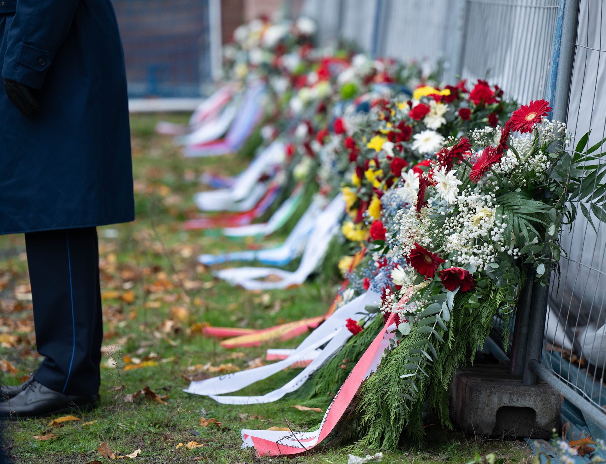 Wreaths rest against a fence before a ceremony.