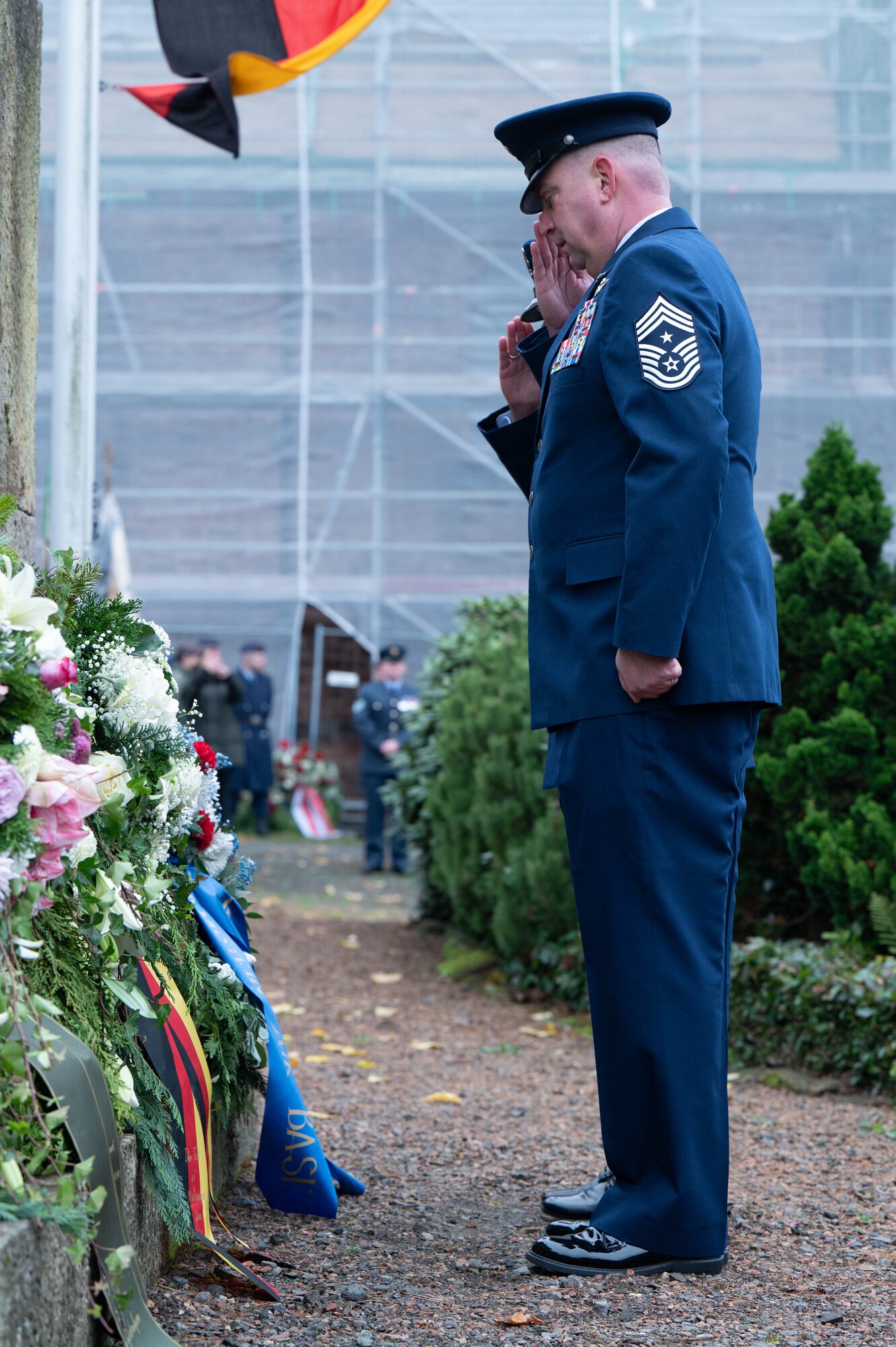 86th Airlift Wing leadership salutes a memorial wreath during a ceremony.