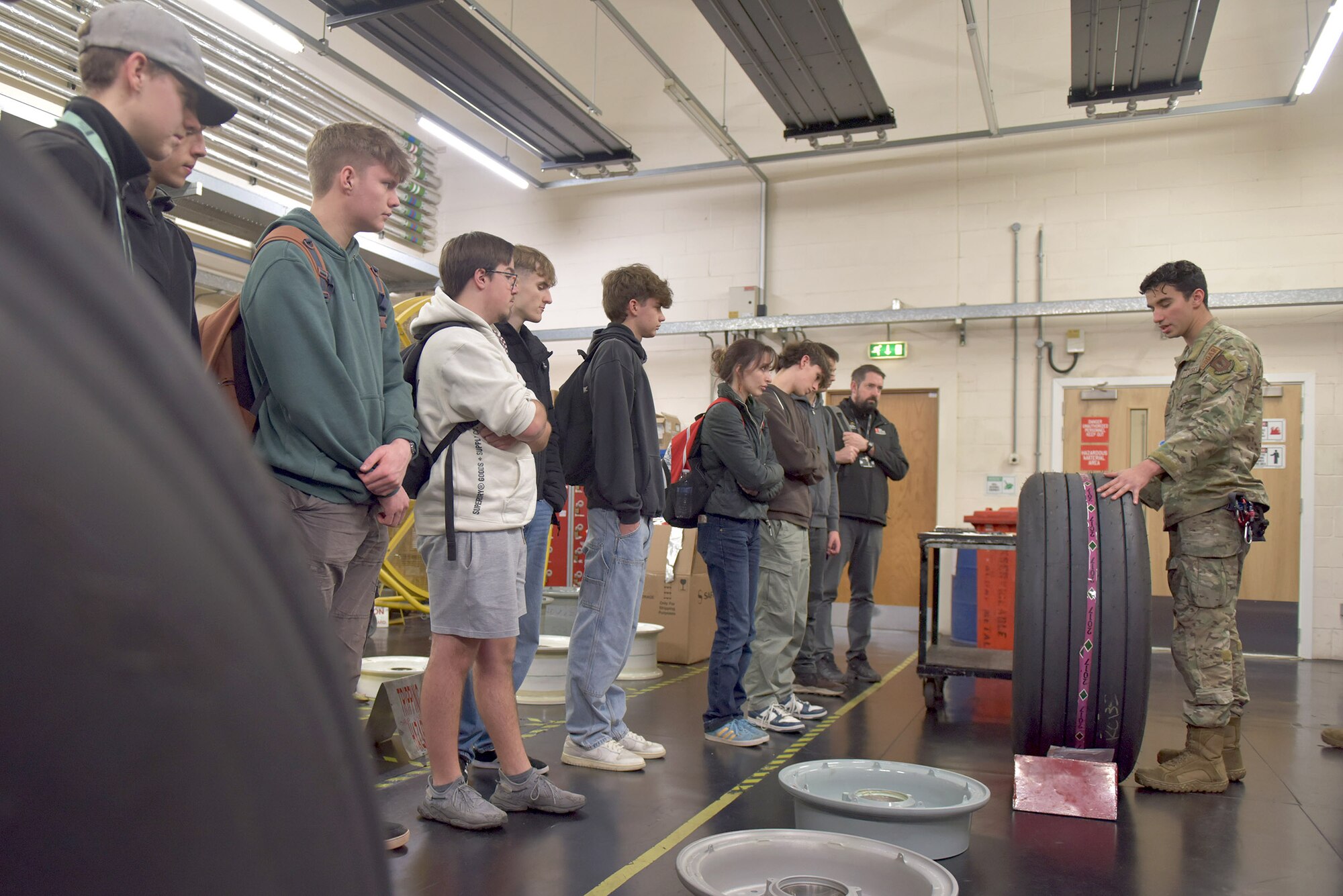 U.S. Air Force Senior Airman Logan Tubbs, right, 100th Maintenance Squadron crew chief, shows the engine of a KC-135 Stratotanker to a group of West Suffolk College engineering students during a tour at Royal Air Force Mildenhall, England, Nov. 15, 2024. The visit was arranged through the Honorary Commander program that pairs unit commanders with prominent members of the local community to enhance relationships between the base and civic leaders. (U.S. Air Force photo by Tech. Sgt. Chris Jacobs)