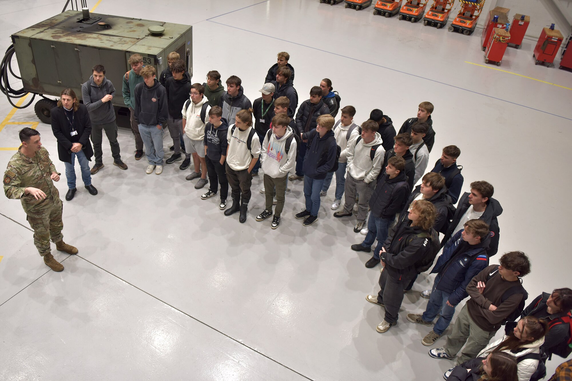 U.S. Air Force Senior Airman Logan Tubbs, right, 100th Maintenance Squadron crew chief, shows the engine of a KC-135 Stratotanker to a group of West Suffolk College engineering students during a tour at Royal Air Force Mildenhall, England, Nov. 15, 2024. The visit was arranged through the Honorary Commander program that pairs unit commanders with prominent members of the local community to enhance relationships between the base and civic leaders. (U.S. Air Force photo by Tech. Sgt. Chris Jacobs)