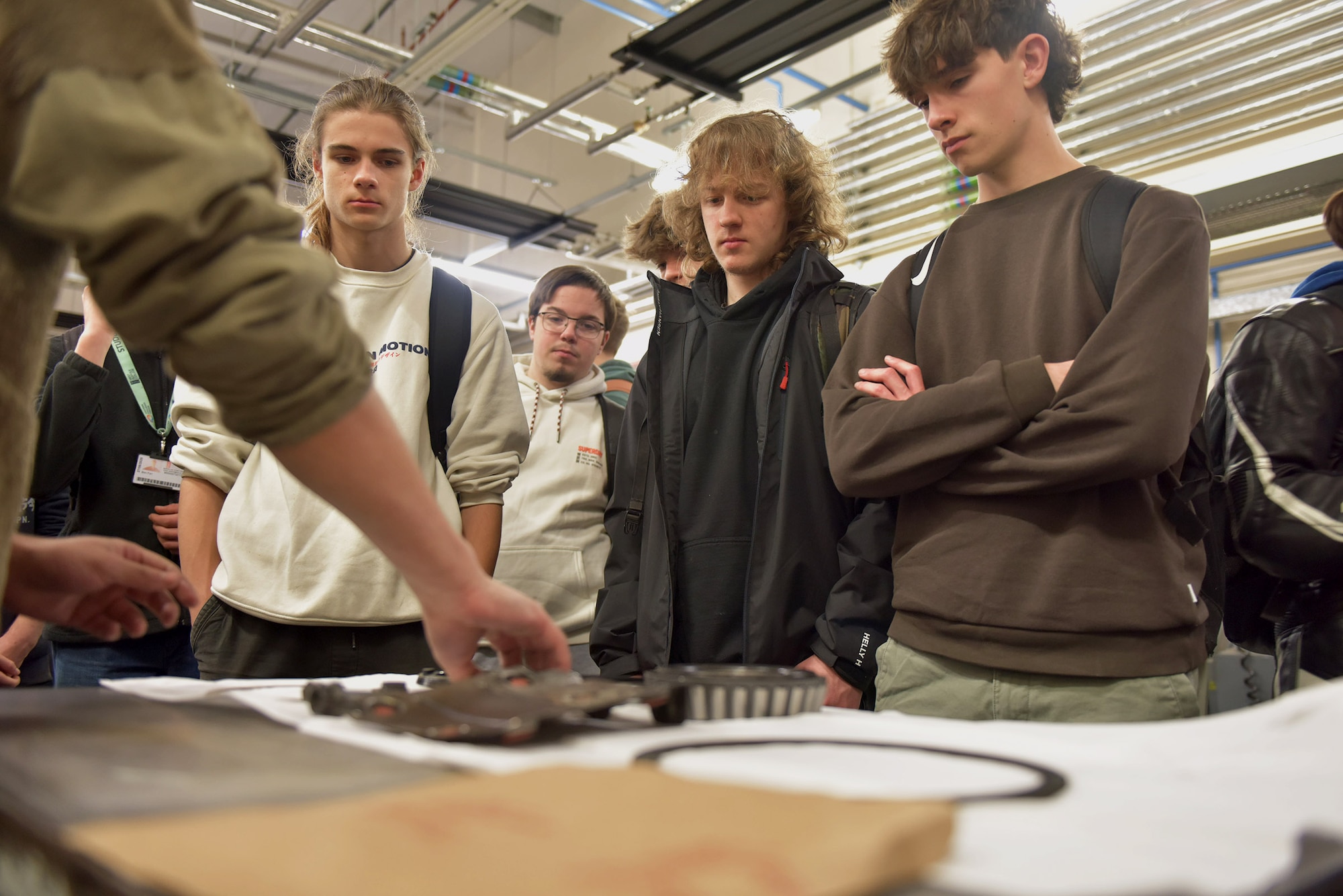 U.S. Air Force Senior Airman Logan Tubbs, right, 100th Maintenance Squadron crew chief, shows the engine of a KC-135 Stratotanker to a group of West Suffolk College engineering students during a tour at Royal Air Force Mildenhall, England, Nov. 15, 2024. The visit was arranged through the Honorary Commander program that pairs unit commanders with prominent members of the local community to enhance relationships between the base and civic leaders. (U.S. Air Force photo by Tech. Sgt. Chris Jacobs)
