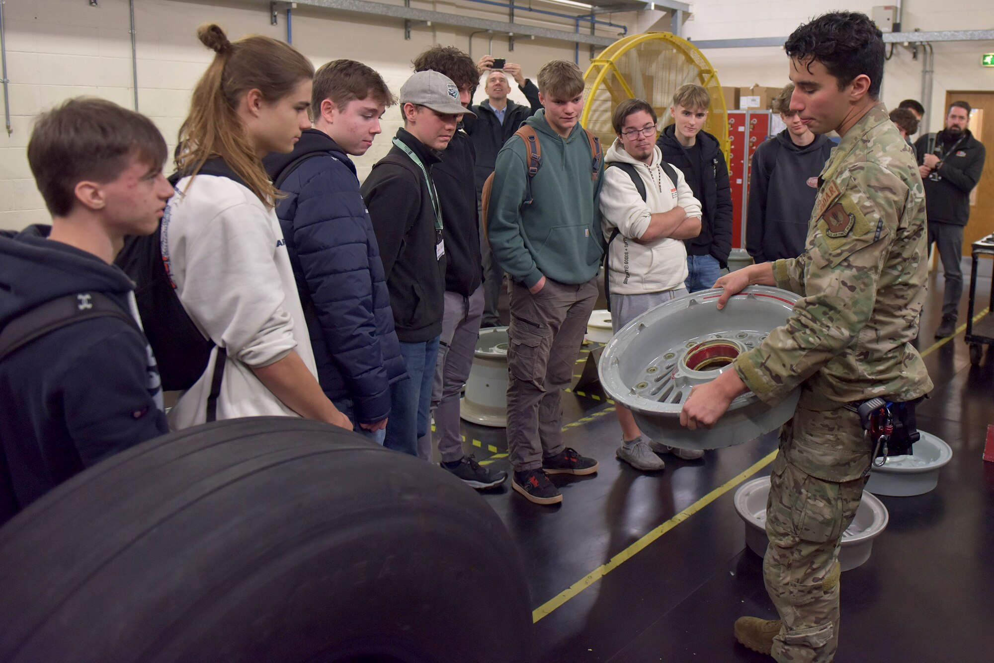 U.S. Air Force Senior Airman Logan Tubbs, right, 100th Maintenance Squadron crew chief, shows the engine of a KC-135 Stratotanker to a group of West Suffolk College engineering students during a tour at Royal Air Force Mildenhall, England, Nov. 15, 2024. The visit was arranged through the Honorary Commander program that pairs unit commanders with prominent members of the local community to enhance relationships between the base and civic leaders. (U.S. Air Force photo by Tech. Sgt. Chris Jacobs)