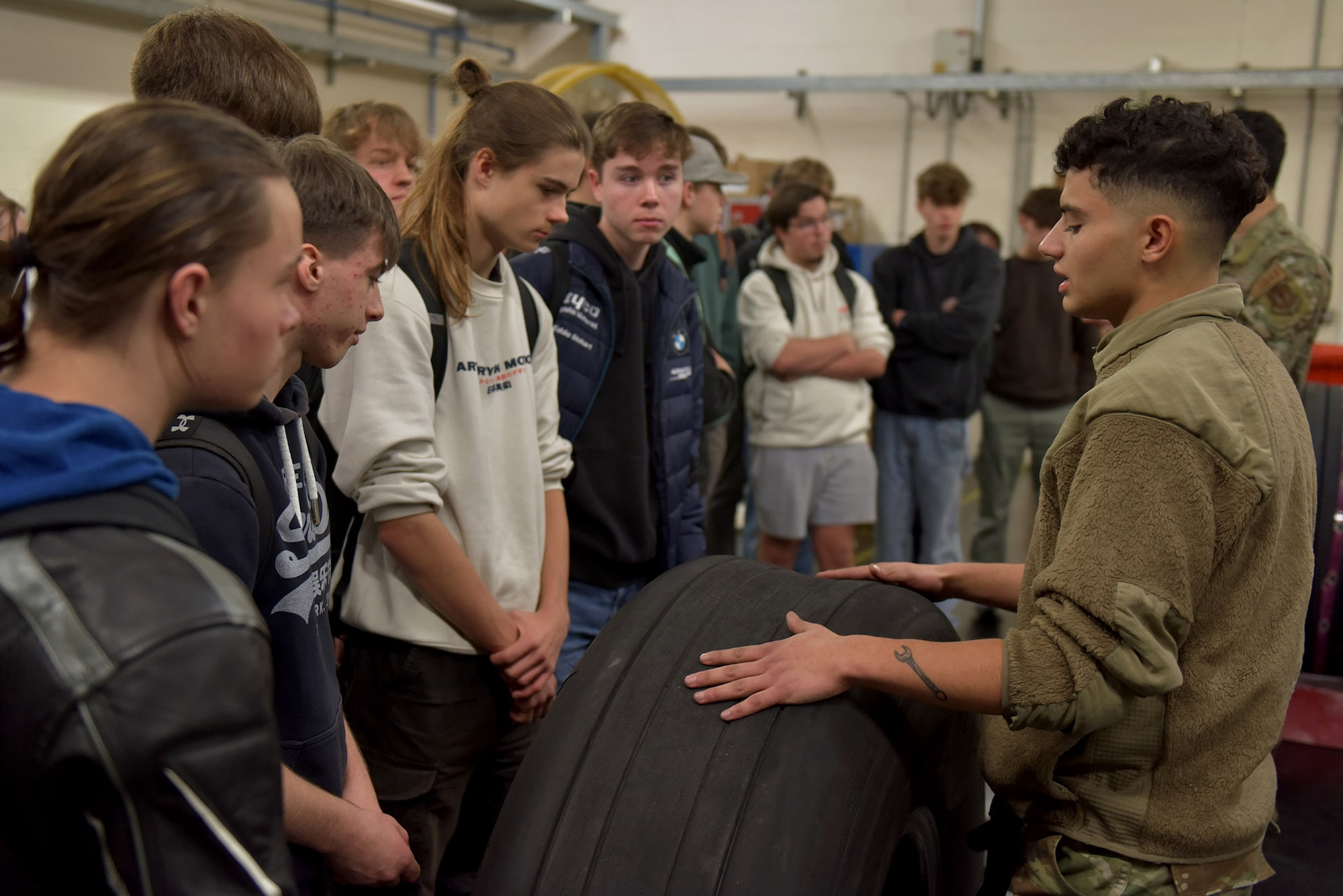 U.S. Air Force Senior Airman Logan Tubbs, right, 100th Maintenance Squadron crew chief, shows the engine of a KC-135 Stratotanker to a group of West Suffolk College engineering students during a tour at Royal Air Force Mildenhall, England, Nov. 15, 2024. The visit was arranged through the Honorary Commander program that pairs unit commanders with prominent members of the local community to enhance relationships between the base and civic leaders. (U.S. Air Force photo by Tech. Sgt. Chris Jacobs)