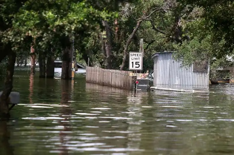 Flooded area with a 15 miles per hour speed limit sign.