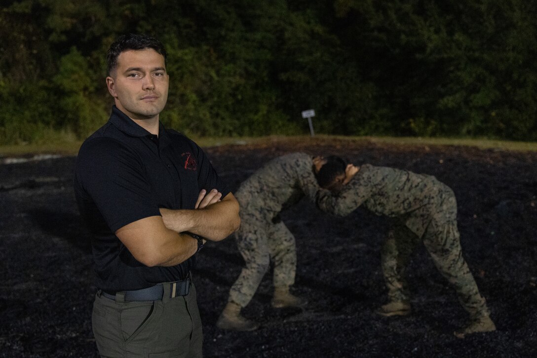 U.S. Marine Corps SSgt. Charles Copeland, a Marine Corps Martial Arts Instructor with the 26th Marine Expeditionary Unit (MEU), poses for a photo while students of his Marine Corps Martial Arts Program course compete in a grappling session, Camp Lejeune, North Carolina, Nov. 7, 2024. Copeland hosted a MCMAP course for Marines of the 26th MEU to advance in their MCMAP belts and prepare them for hand-to-hand combat. (U.S. Marine Corps photo by Lance Cpl. Osmar VasquezHernandez)