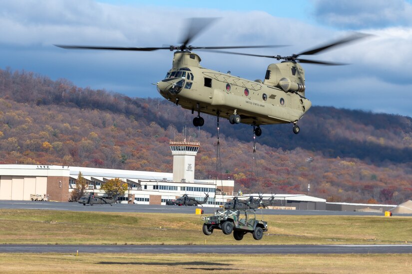 A CH-47 Chinook helicopter sling-loads a Humvee during an open house at Fort Indiantown Gap, Pennsylvania, Nov. 16, 2024. This free event featured Miss Pennsylvania, live tactical demonstrations, flyovers, displays of military equipment and vehicles, food trucks, live music and a performance by the Pennsylvania National Guard’s Ambassador Demonstration Team. (U.S. Army National Guard photo by Wayne V. Hall)