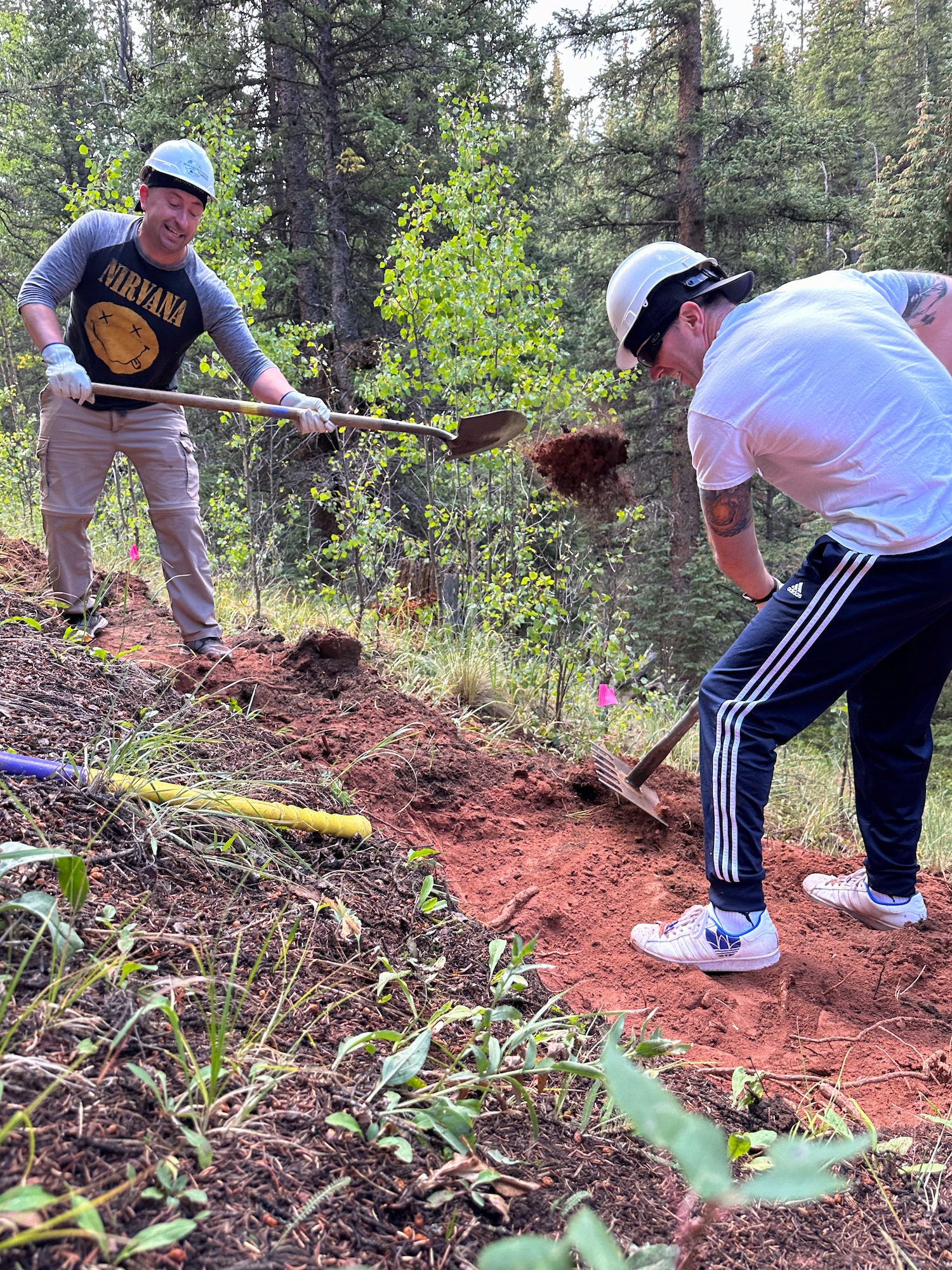 Two individuals shoveling dirt.
