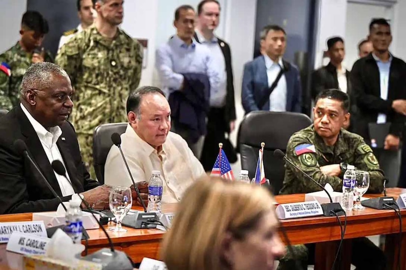 Two men wearing business attire are seated at a conference table.