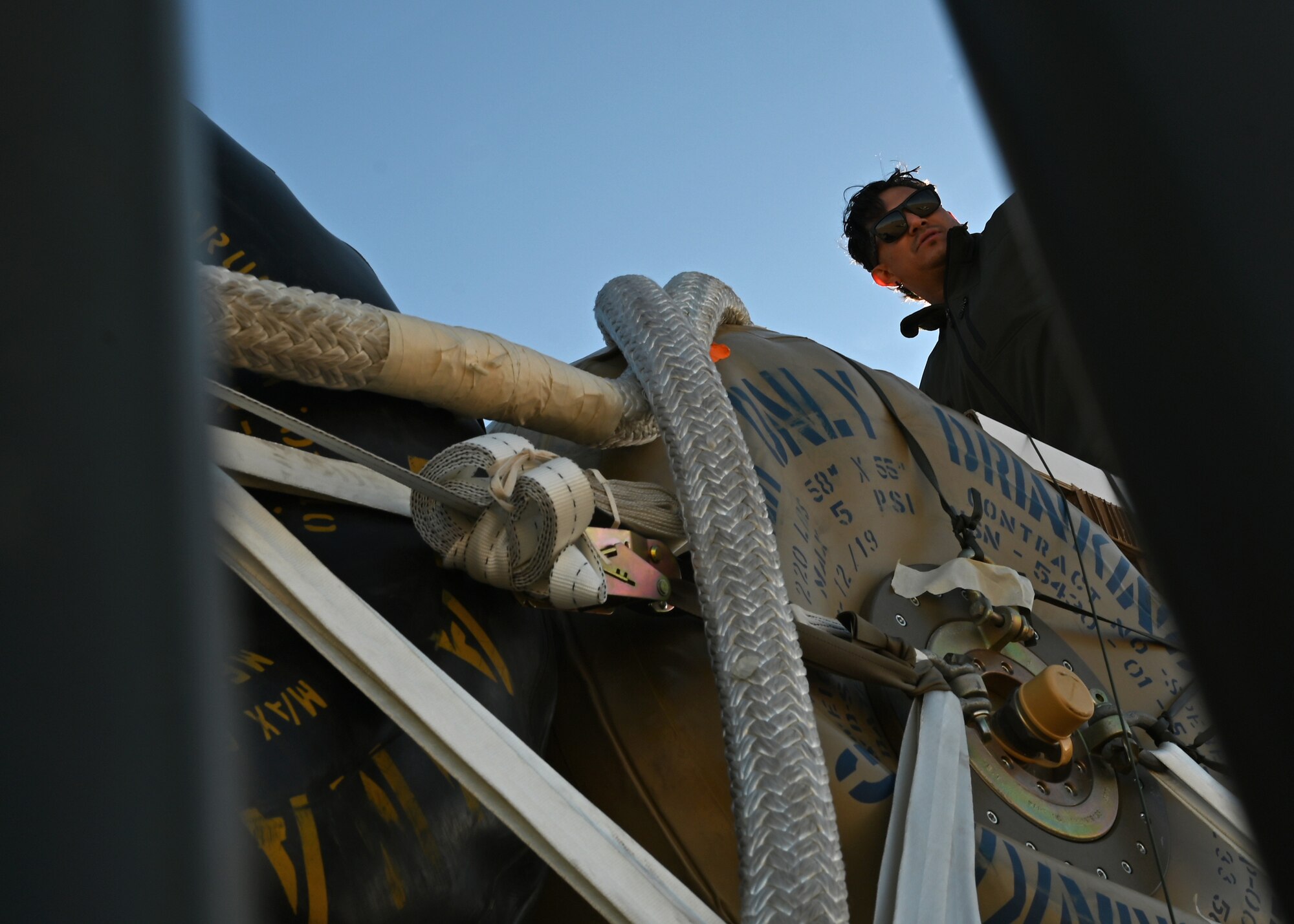 A member assigned to the U.S. Army Yuma Proving Ground (YPG) inspects cargo at Davis-Monthan Air Force Base, Arizona, Nov. 6, 2024. DMAFB assisted the Army Test and Evaluation Command and US Army Combat Capabilities Development Command Soldier Center (DEVCOM SC) to test a 40-foot platform in load and airdrop capabilities in support of a US Transportation Command funded project. (U.S. Air Force photo by Staff Sgt. Abbey Rieves)
