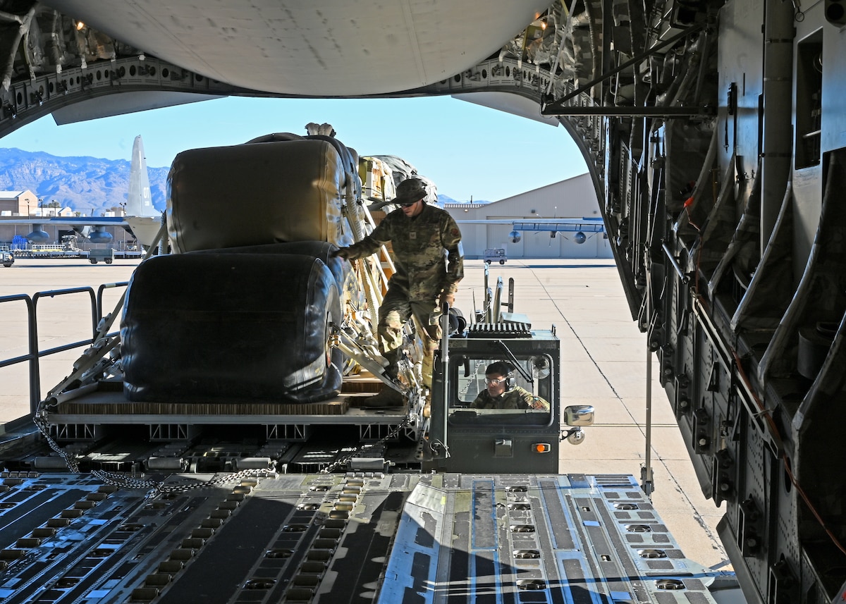 U.S. Air Force Staff Sgt. Harry Edmondson, 355th Logistics Readiness Squadron noncommissioned officer in charge of air transportation function operations, left, directs cargo movement to Airman 1st Class Emanuel Garcia, 355th LRS air terminal function representative, right, at Davis-Monthan Air Force Base, Arizona, Nov. 6, 2024. Edmondson and Gracia advanced their agile combat employment by helping the U.S. Army Test and Evaluation Command and U.S. Army Combat Capabilities Development Command Soldier Center with loading 49,500 pounds on an C-17 Globemaster III aircraft. This multi-agency and joint collaboration advanced capabilities across the Department of Defense in support of a U.S. Transportation Command funded project. (U.S. Air Force photo by Staff Sgt. Abbey Rieves)