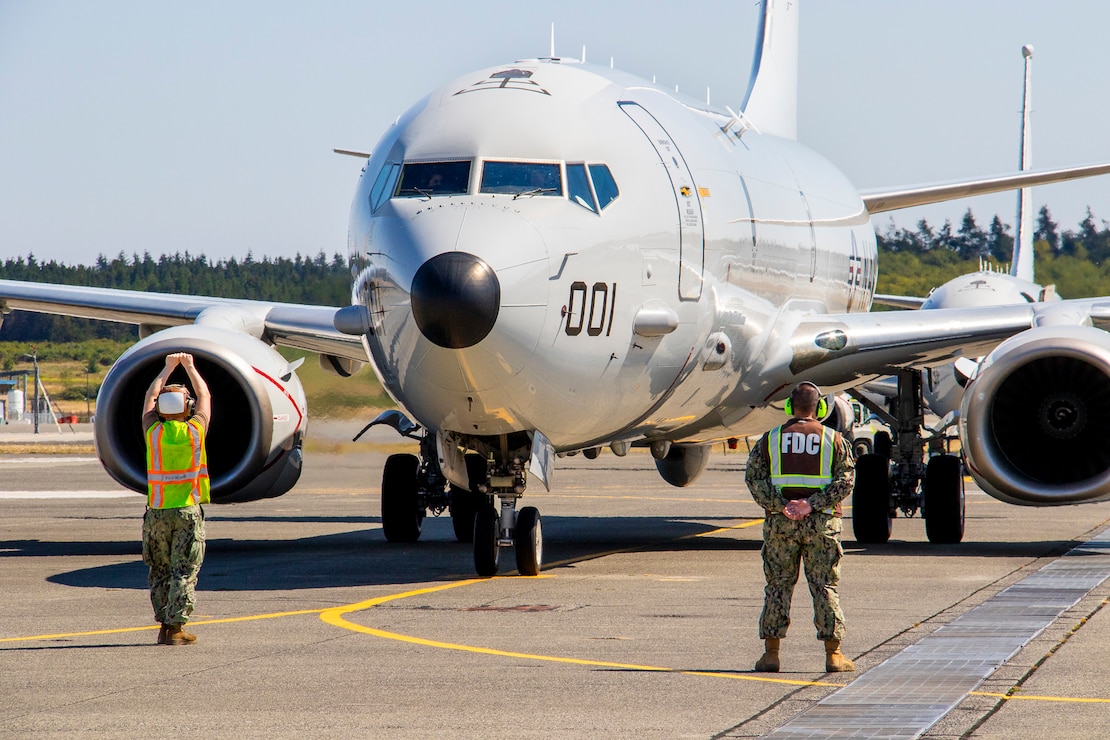 Aviation Machinist Mate 3rd Class Alexander Schrama (left), a Sailor assigned to Patrol Squadron (VP) 46, the ‘Grey Knights,’ directs a P-8A Poseidon to a parking spot while Logistics Specialist Chief Joseph Aceron observes for safety at Naval Air Station Whidbey Island, Washington, Aug. 9, 2024. The aircraft was returning from a flight conducting intelligence, reconnaissance and surveillance. (U.S. Navy photo by Mass Communication Specialist 2nd Class Jacquelin Frost.)