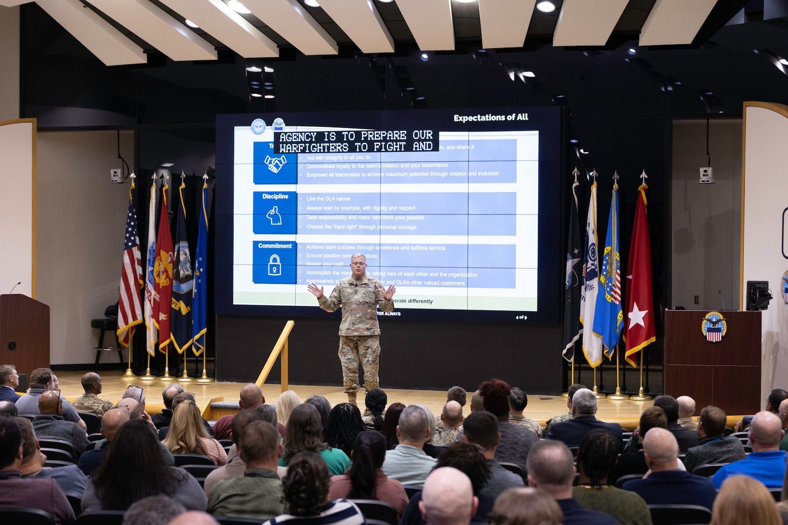 A light skinned man with graying hair in uniform speaks on stage.