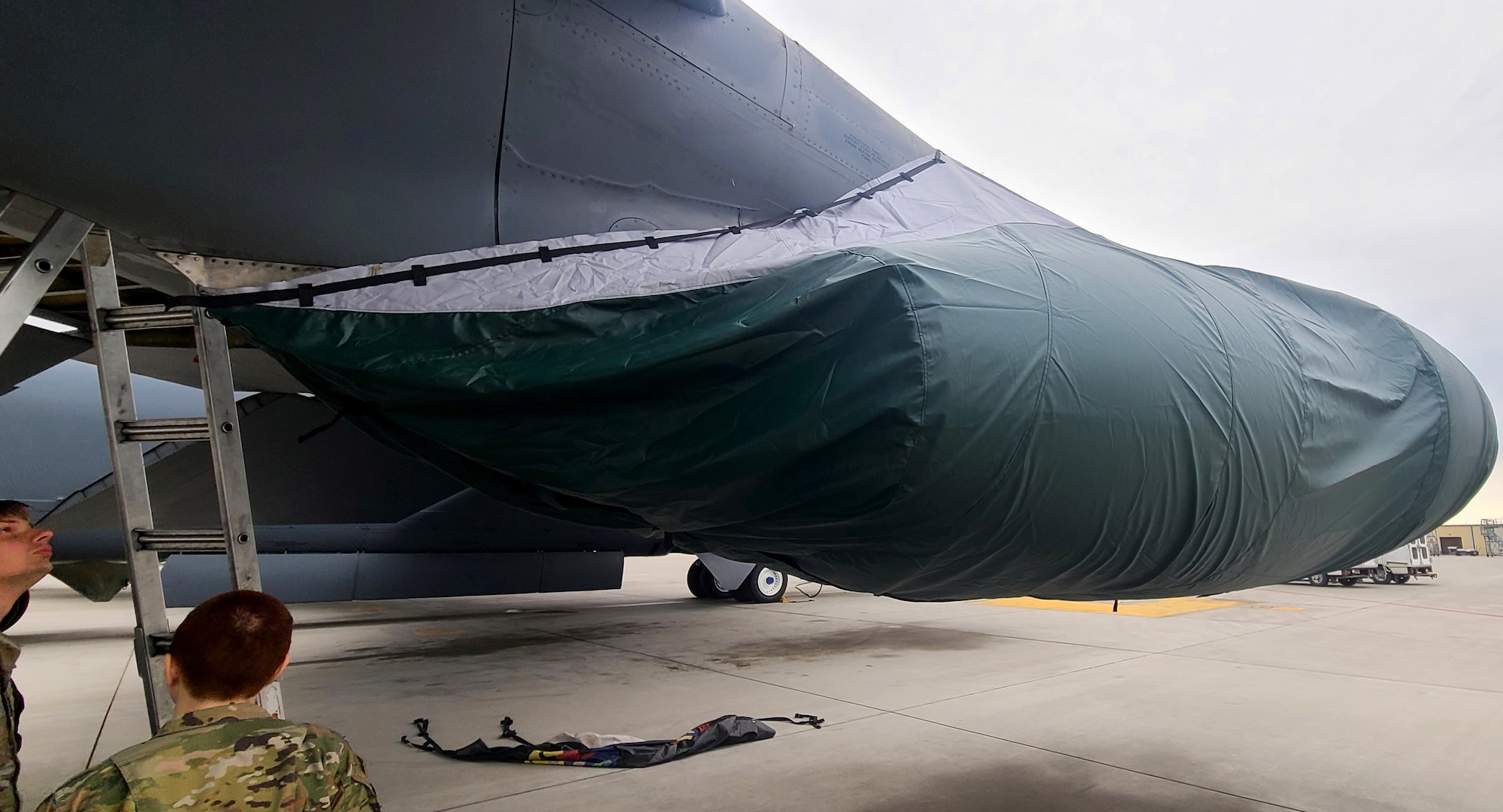 People stand around a B-52 Stratofortress that has a covered engine.