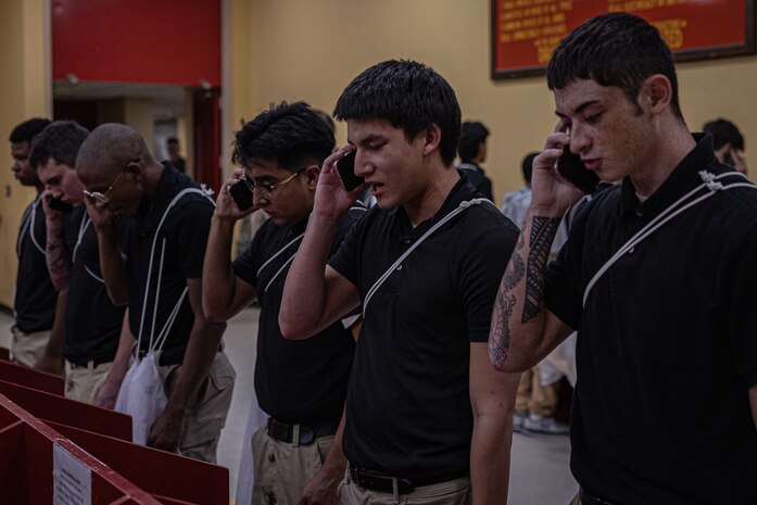 New U.S. Marine Corps recruits with Echo Company, 2nd Recruit Training Battalion, make their scripted phone calls home as part of a receiving event at Marine Corps Recruit Depot San Diego, California, Nov. 4, 2024. During the receiving process, recruits are checked for contraband, given a haircut, make a scripted phone calls home, and issued their gear required for training. (U.S. Marine Corps photo by Lance Cpl. Jacob B. Hutchinson)