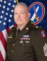 Official photo of Command Sgt. Major Vern B. Daley in front of the U.S. Flag and the Military District of Washington flag.