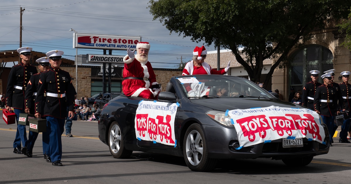 Santa Claus and Mrs. Claus wave as U.S. Marines assigned to Goodfellow Air Force Base collect donations for Toys for Tots during the Veterans Day Parade in downtown San Angelo, Texas, Nov. 9, 2024. The Marine Toys for Tots Foundation was started in 1947 by Maj. Bill Hendrick, who collected and distributed 5,000 toys with the Marines in his reserve unit in Los Angeles. (U.S. Air Force photo by Staff Sgt. Nathan Call)
