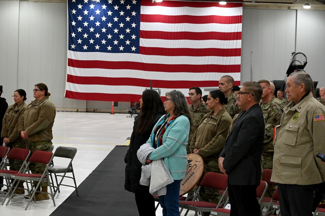 People stand and listen to a drum and singing.