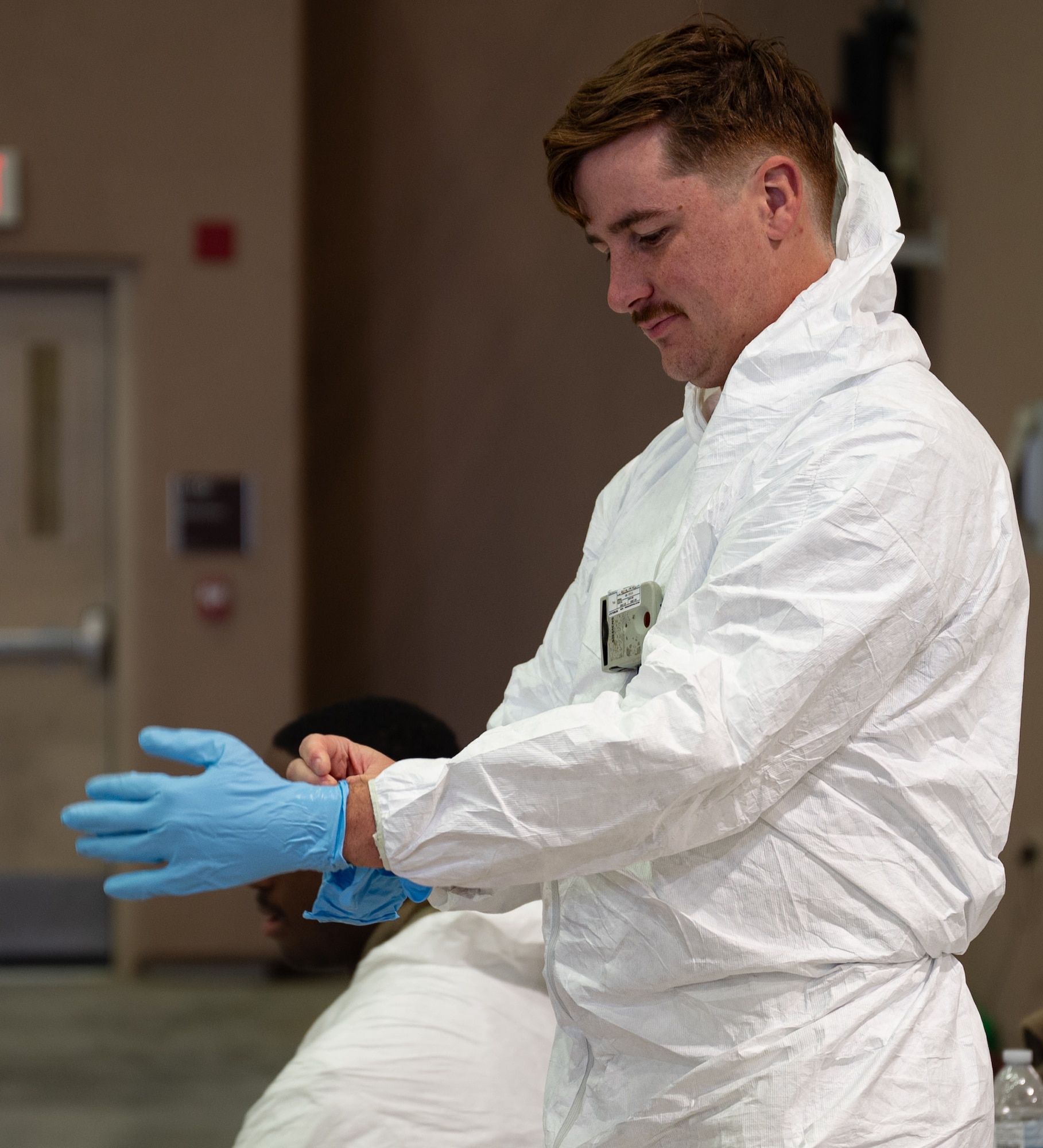 A U.S. Air Force Airman assigned to the 51st Civil Engineer Squadron puts on personal protective equipment during Radiant Falcon at Osan Air Base, Republic of Korea, Nov. 14, 2024. Radiant Falcon is a cross-functional training event designed to protect personnel while maintaining airpower in a simulated nuclear environment. (U.S. Air Force photo by Senior Airman Brittany Russell)