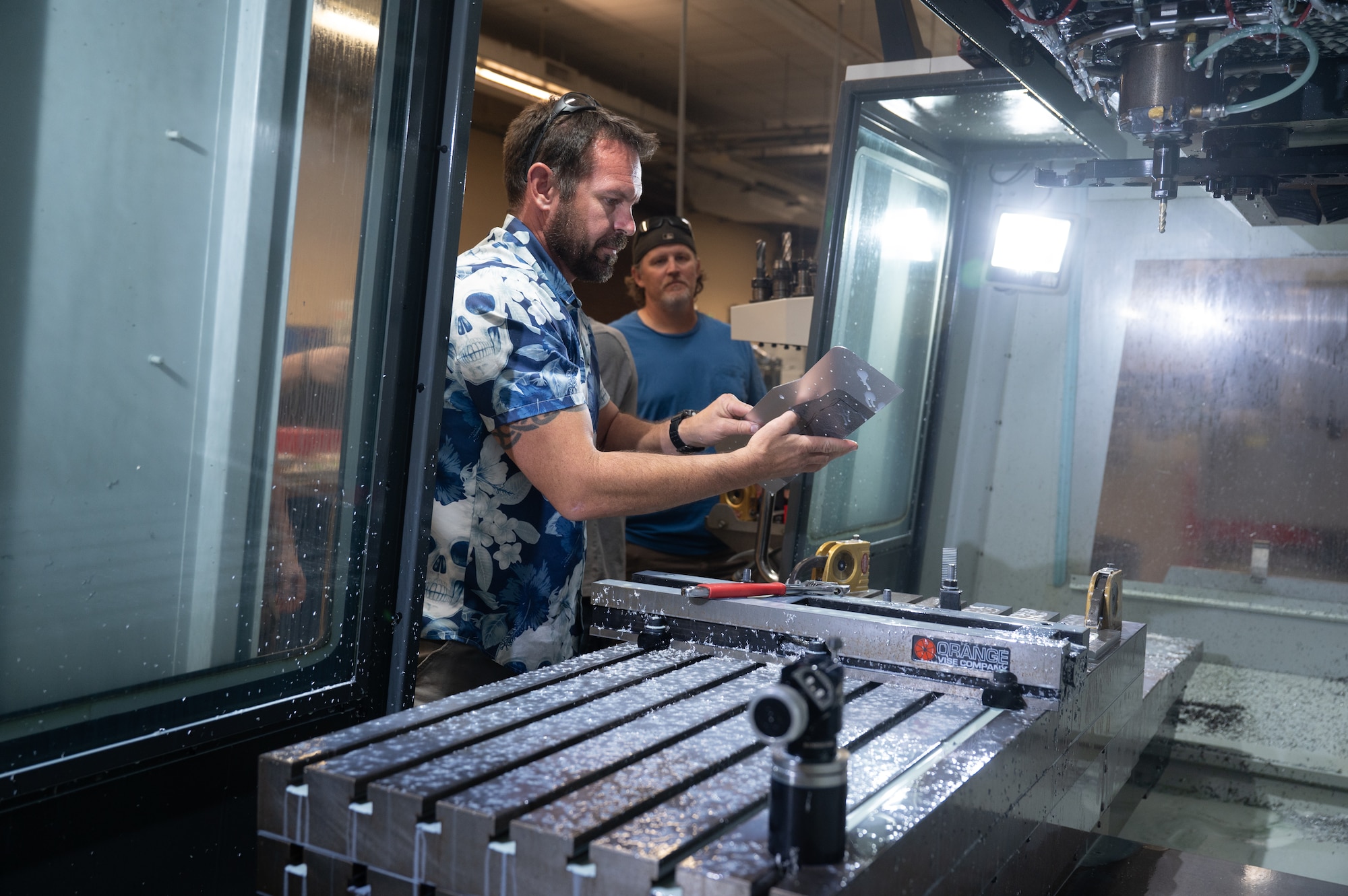 Three personnel members use a machine in the 15th Maintenance Group building.
