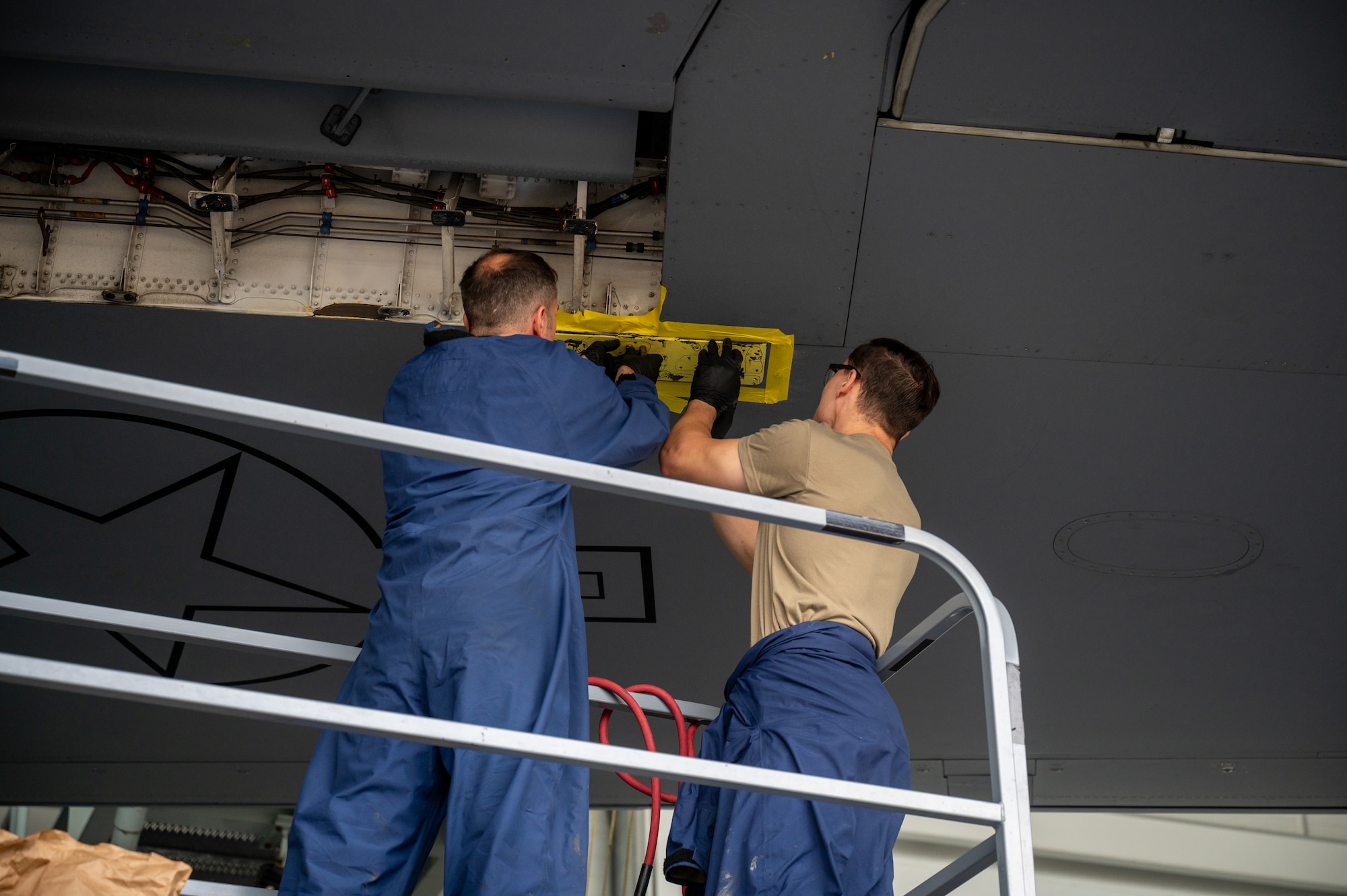 Two maintainers work on an aircraft.