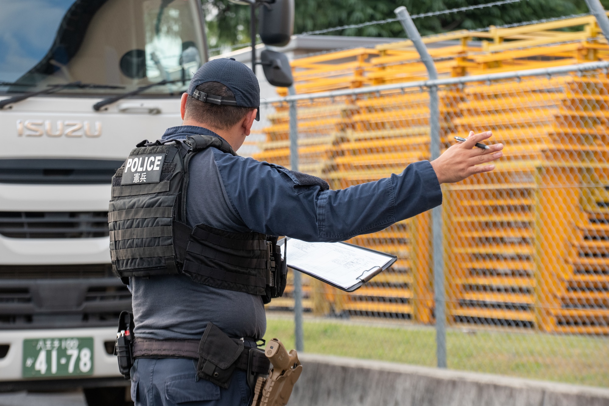 A Japanese civilian guard dressed in black signals a commercial truck to enter the inspection area at the Yokota supply gate.