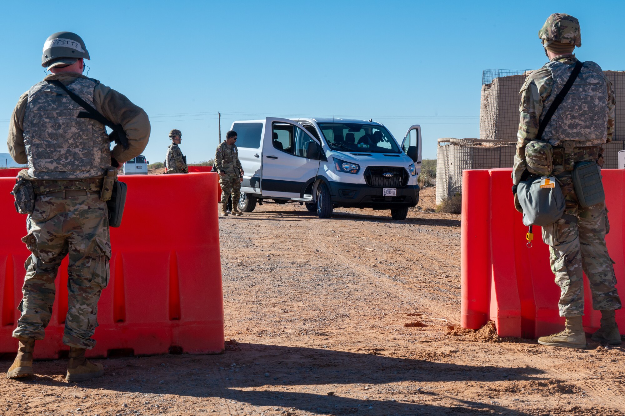 U.S. Airmen assigned to the 11th Air Task Force stand guard at an entry control point as teammates search a vehicle during the 11th ATF’s first field exercise at McGregor Range, New Mexico, Nov. 9, 2024. The search ensured no threats were able to compromise the base. (U.S. Air Force photo by Airman 1st Class Jasmyne Bridgers-Matos)