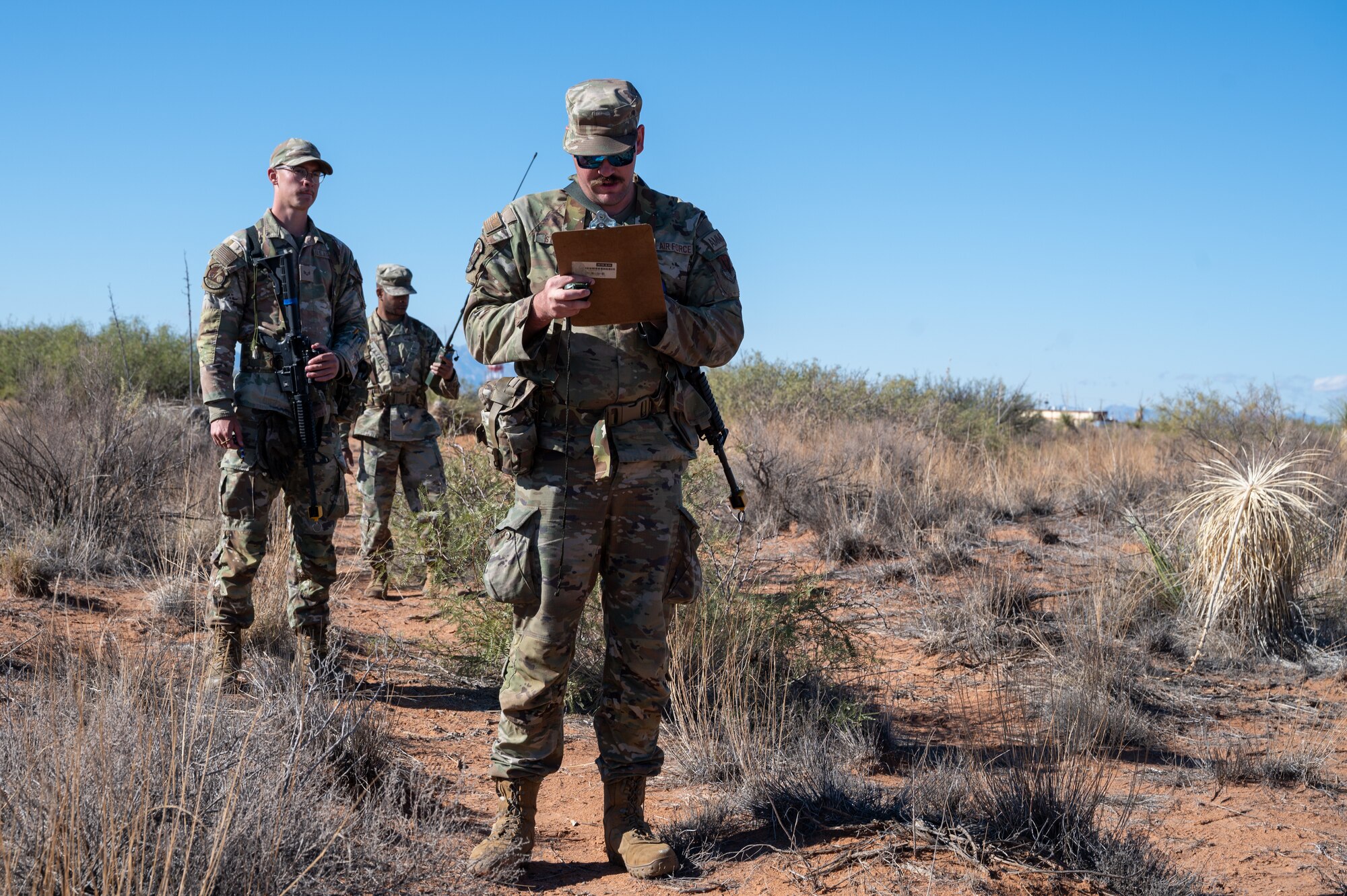 U.S. Air Force Senior Airman Kaden Heath, left, Master Sgt. Joshua Dennis, center, Staff Sgt. Justin Stoeckle, right, 11th Air Task Force members, follow their map to locate coordinates during the land navigation portion of the 11th ATF’s first field exercise at McGregor Range, New Mexico, Nov. 8, 2024. Airmen were given a map, compass and protractor to find their assigned coordinates. (U.S. Air Force photo by Airman 1st Class Jasmyne Bridgers-Matos)