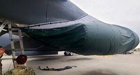 People stand around a B-52 Stratofortress that has a covered engine.