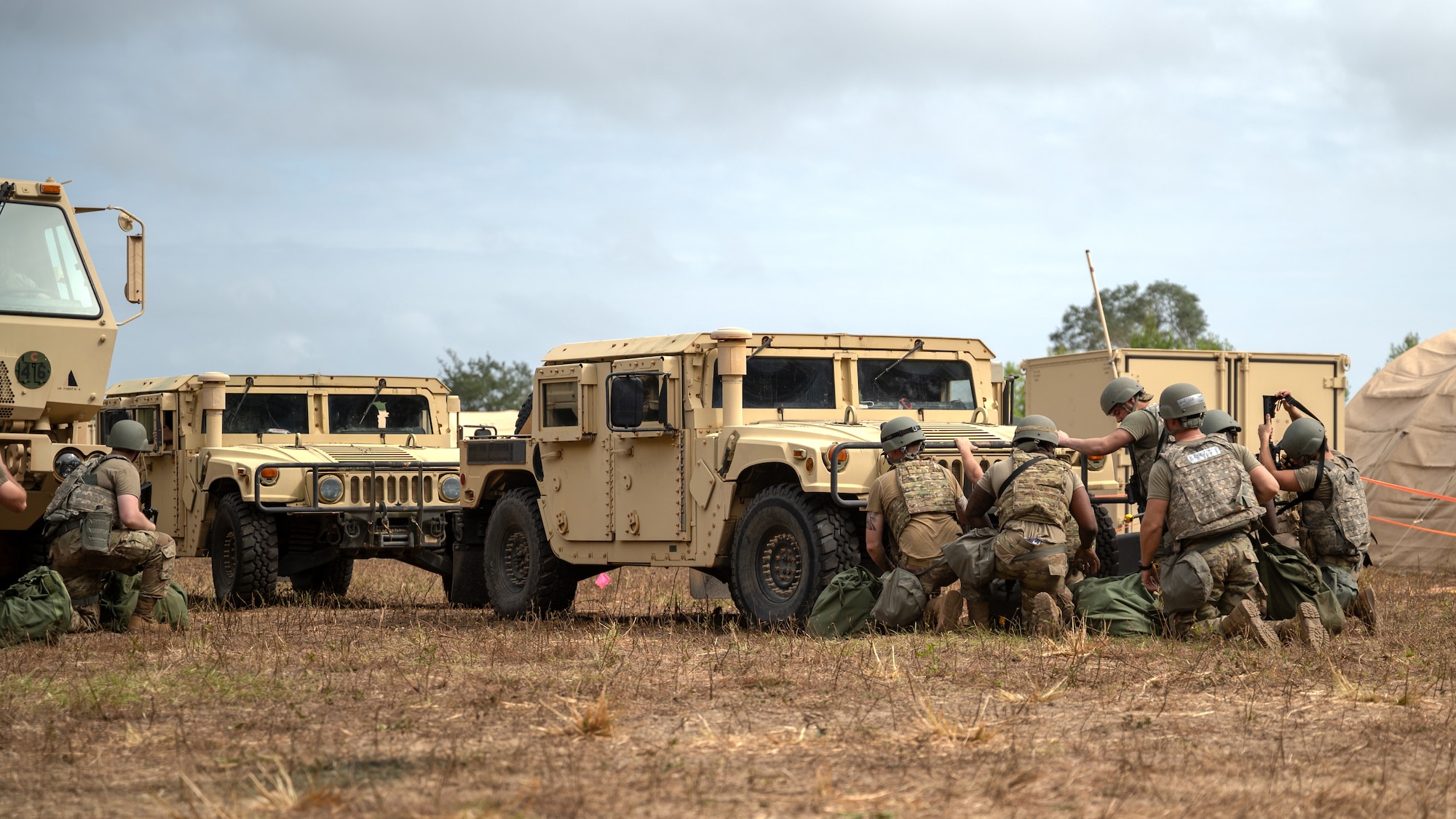 U.S. Airmen, assigned to the 1st Special Operations Mission Support Group, take cover behind a humvee after hearing explosives during a bivouac exercise at Eglin Range, Eglin Air Force Base, Florida, Nov. 5, 2024.