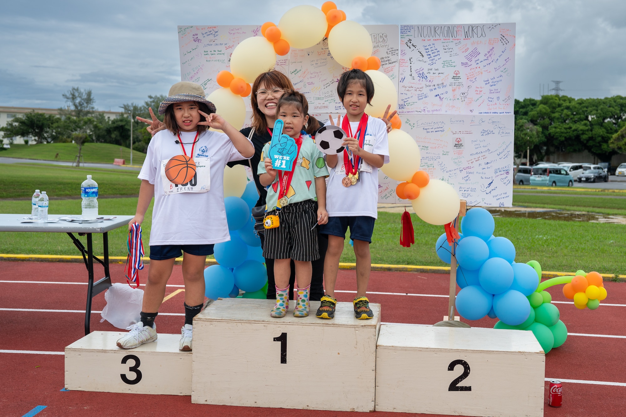 three Kadena Special Olympics children and one volunteer pose for a photo with their medals.