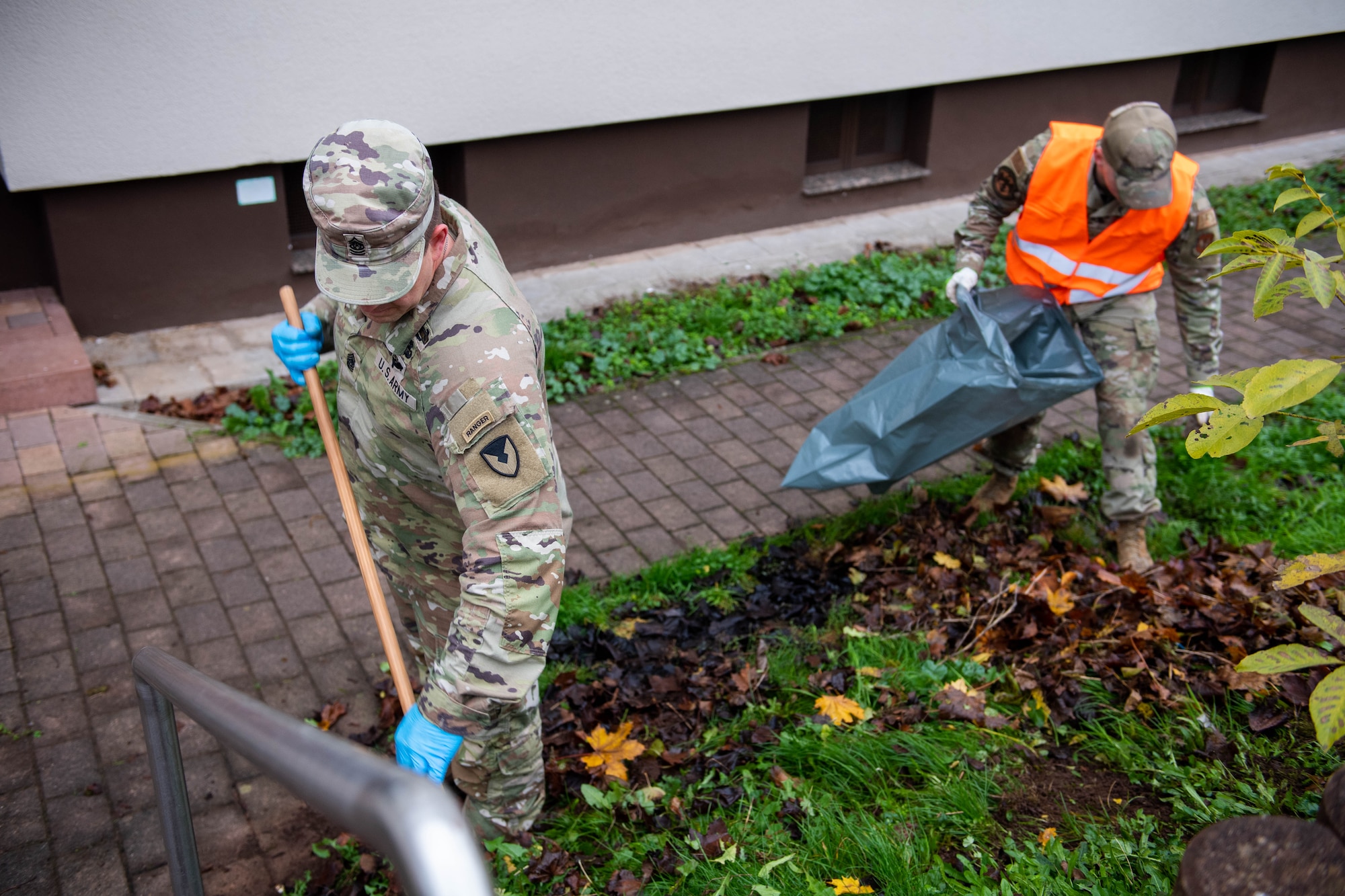 Military members rake leaves.