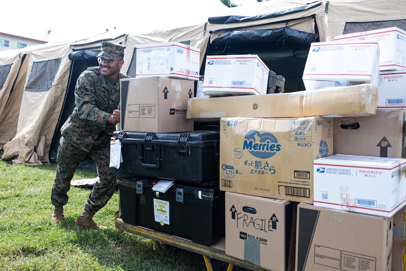 A Marine moves dozens of packages on a cart.