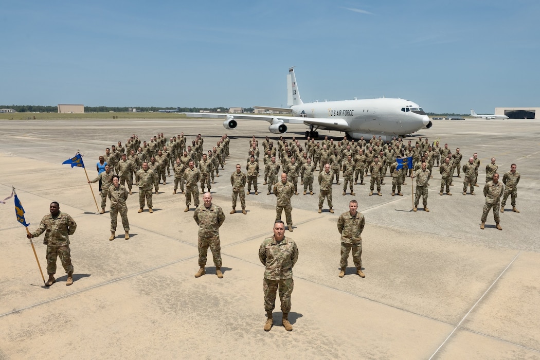 Photo shows Airmen in uniform standing in formation in front of aircraft on flight line.