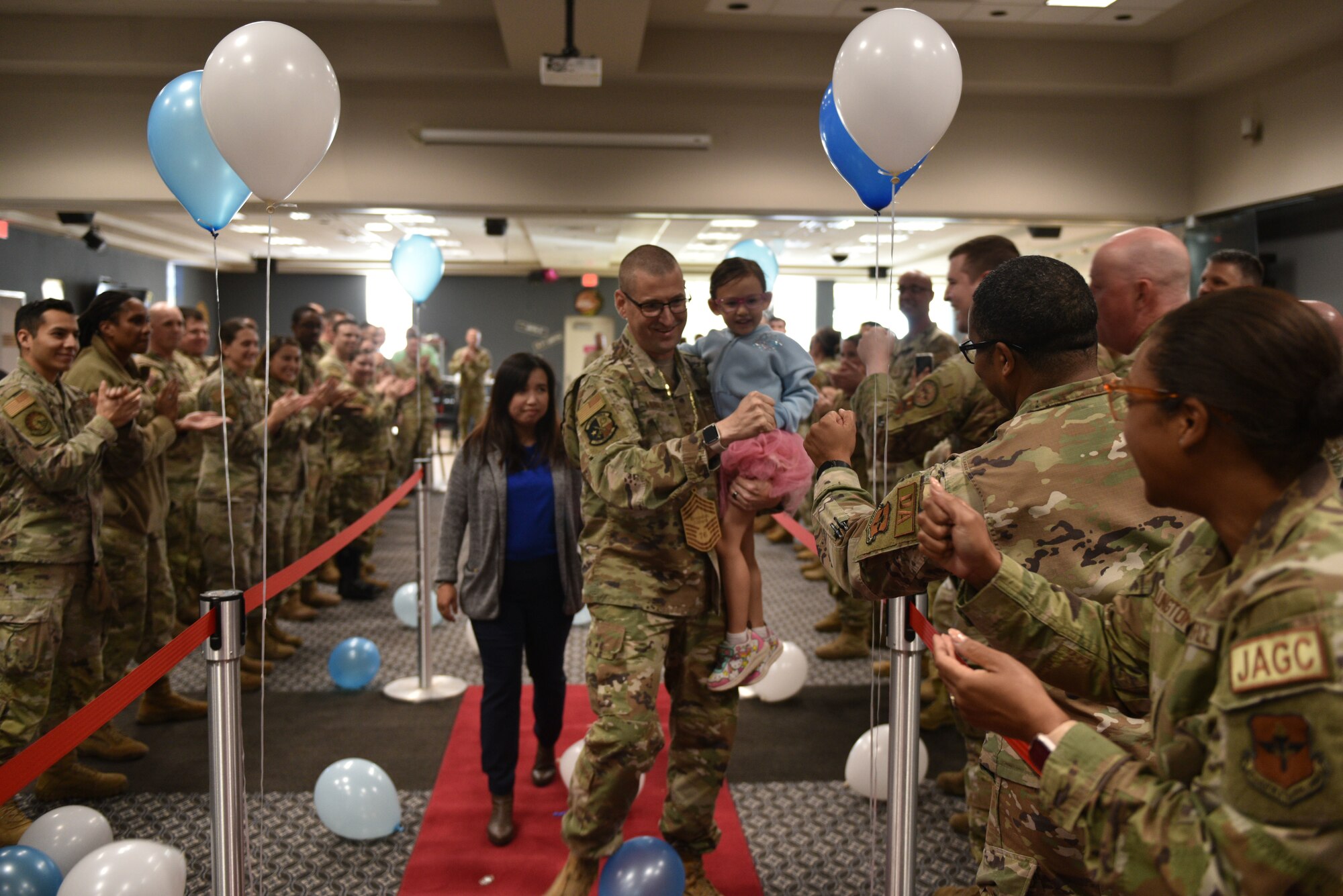 U.S. Air Force Chief Master Sgt. Select Brandon Abbott, 316th Training Squadron operations superintendent, walks down the red carpet with his family as members of the 17th Training Wing applaud him during the Chief Release Party at the Powell Event Center, Goodfellow Air Force Base, Texas, Nov. 18, 2024. Abbott was one of 503 personnel selected for promotion to chief master sergeant in the 2024 promotion cycle. (U.S. Air Force photo by 1st Lt. Harris Hillstead)