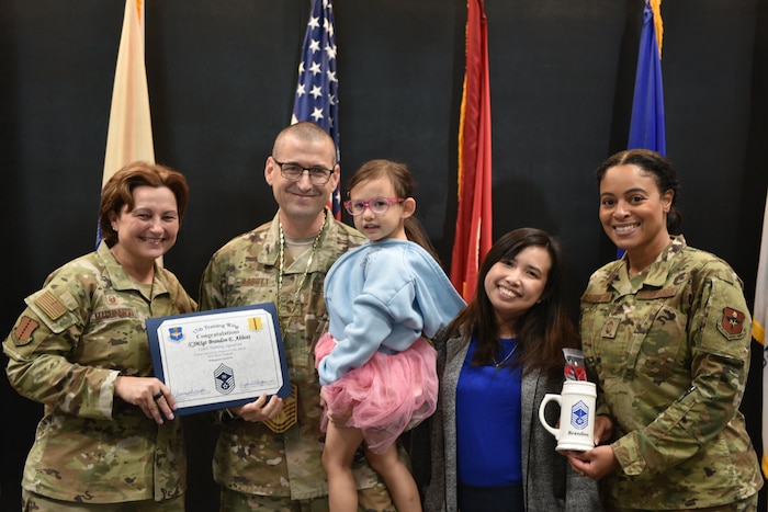 U.S. Air Force Col. Angelina Maguinness, 17th Training Wing commander, and Chief Master Sgt. Khamillia Washington, 17th TRW command chief, present a certificate of promotion and mug to Chief Master Sgt. Select Brandon Abbott, 316th Training Squadron operations superintendent, and his family during the Chief Release Party at the Powell Event Center, Goodfellow Air Force Base, Texas, Nov. 18, 2024. Abbott was one of 503 personnel selected for promotion to chief master sergeant in the 2024 promotion cycle. (U.S. Air Force photo by 1st Lt. Harris Hillstead)