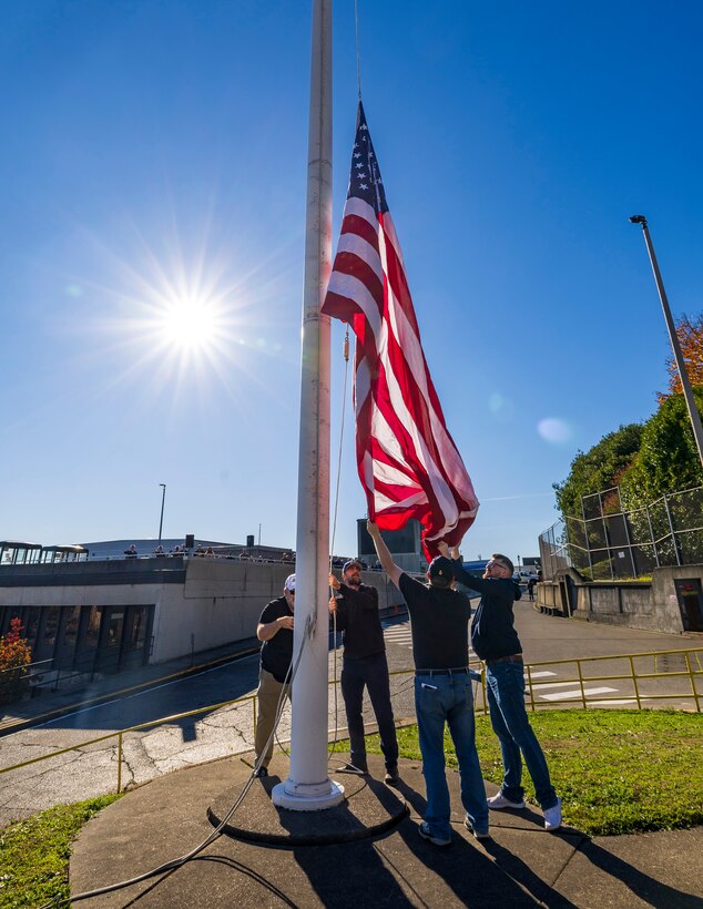 Honor guard members fold the U.S. flag Nov. 7, 2024, during a Veterans Day observance at Puget Sound Naval Shipyard & Intermediate Maintenance Facility in Bremerton, Washington. The event, hosted by the Veterans Employee Resource Group, featured a special flag-folding ceremony at the State Street Gate entrance. (U.S. Navy photo by Wendy Hallmark)