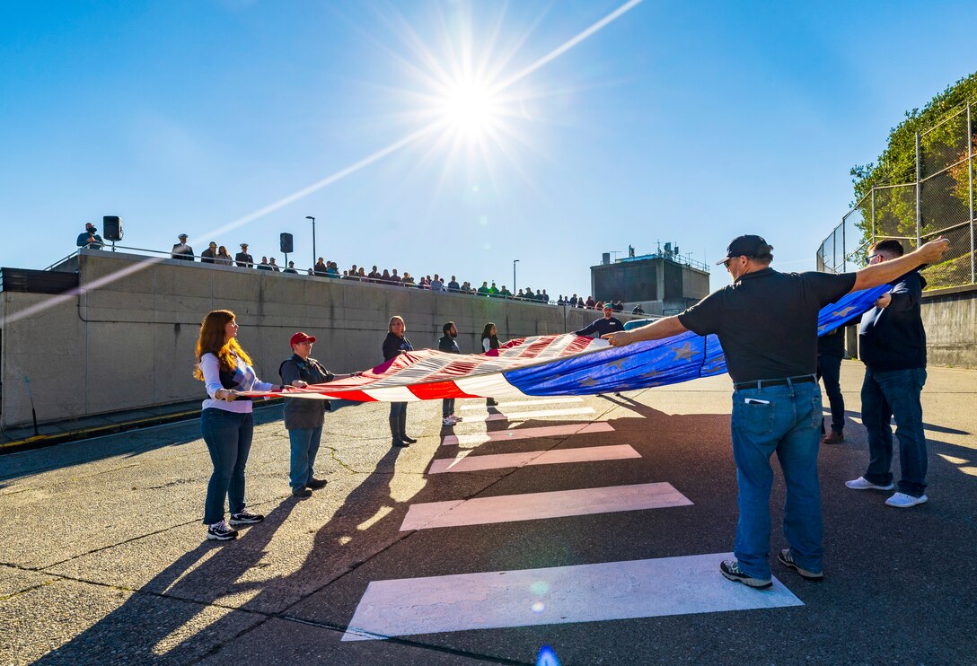 Honor guard members fold the U.S. flag Nov. 7, 2024, during a Veterans Day observance at Puget Sound Naval Shipyard & Intermediate Maintenance Facility in Bremerton, Washington. The event, hosted by the Veterans Employee Resource Group, featured a special flag-folding ceremony at the State Street Gate entrance. (U.S. Navy photo by Wendy Hallmark)