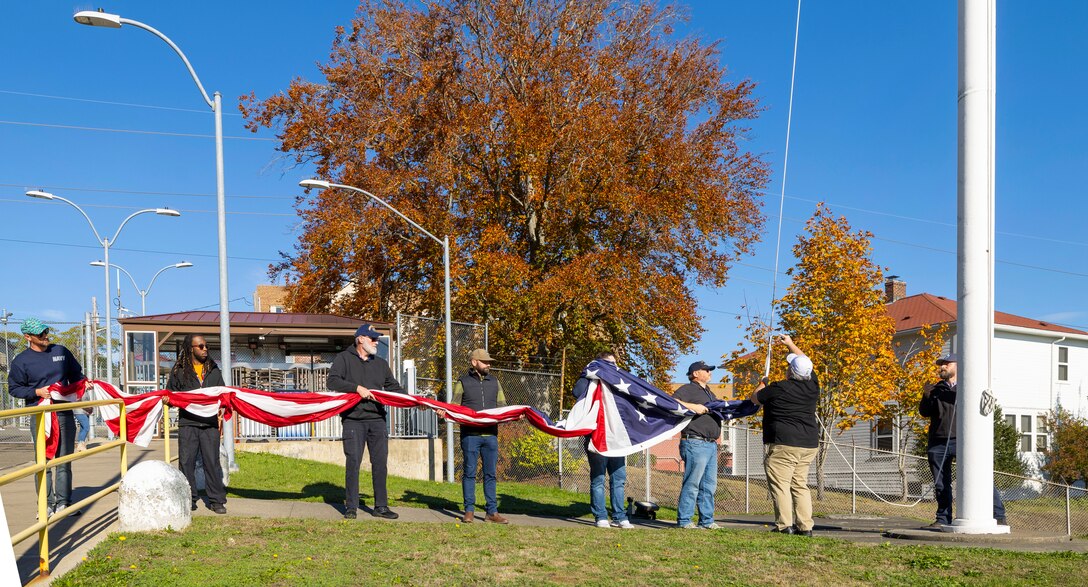 Honor guard members fold the U.S. flag Nov. 7, 2024, during a Veterans Day observance at Puget Sound Naval Shipyard & Intermediate Maintenance Facility in Bremerton, Washington. The event, hosted by the Veterans Employee Resource Group, featured a special flag-folding ceremony at the State Street Gate entrance. (U.S. Navy photo by Wendy Hallmark)