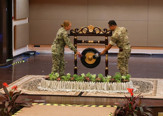 U.S. Navy Rear Adm. Katie Sheldon, Vice Commander, U.S. 7th Fleet, rings the ceremonial gong with the Chief of Staff, joint force headquarters, Royal Brunei Armed Forces, during the opening ceremony of Cooperation Afloat Readiness and Training (CARAT) Brunei 2024 at Wira Seni Hall, RBAF Band, Bolkiah Garrison, Brunei, Nov. 18.